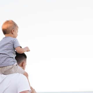 Child on Father Shoulder Raising a Happy Child